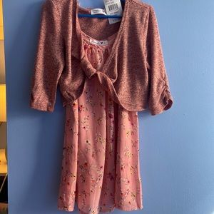 Pink blouse with a pink cover up the blouse has flowers on  it